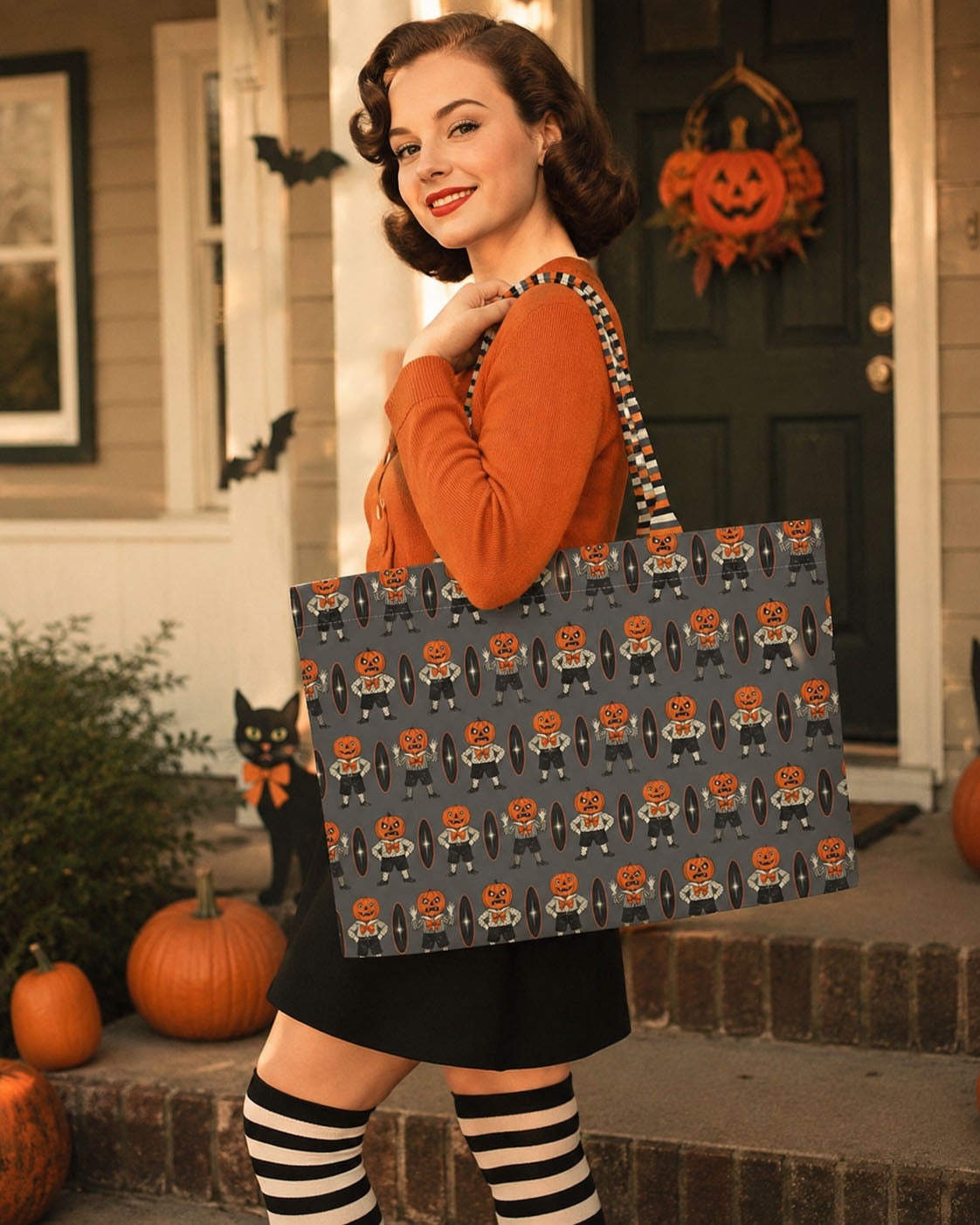 Everyday luxe tote held at side, gray with orange jack-o-lantern character pattern
